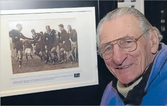  ?? Photos: GISBORNE HERALD ?? Famous victory: Richard ‘Tiny’ White with a photo of himself, second from left in head gear, from the first test against South Africa in Dunedin in 1956. The All Blacks won that match 10-6.