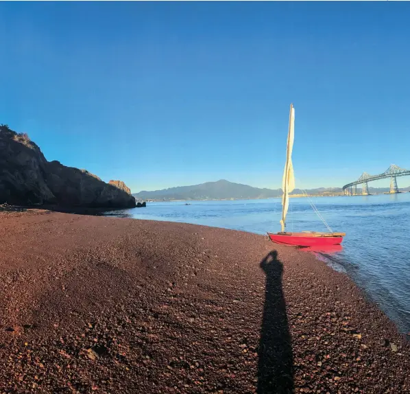  ??  ?? Red beach, red boat: Puff takes a breather on the shore of Red Rock Island with the Richmond-san Rafael Bridge beyond.