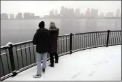  ?? (AP/Michael Dwyer) ?? Two people look out Friday over Boston Harbor and the city skyline in Piers Park in Boston.