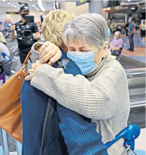  ?? ?? Families embrace after a flight from Los Angeles arrived at Auckland airport as New Zealand’s border opened for visa-waiver countries, including the UK