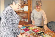  ?? CAROLE MORRIS-UNDERHILL ?? Beth McBrine and Cathy Dunbar meticulous­ly go over the layout and design of each fidget quilt, ensuring patches with zippers, bobbles and texture are lined up in a specific manner. Each quilt piece is then sewn together multiple times and inspected...