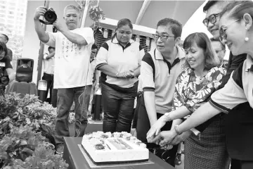  ??  ?? Teo (third left) and others cut a cake to declare openthe new gate.
