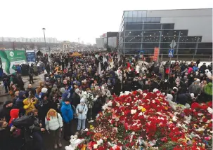  ?? (Maxim Shemetov/Reuters) ?? PEOPLE GATHER at a makeshift memorial to the victims of a shooting attack set up outside the Crocus City Hall concert venue yesterday.