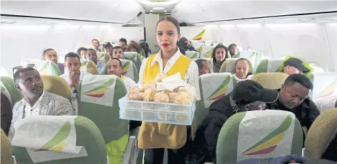  ??  ?? A flight attendant serves passengers breakfast inside Ethiopian Airlines ET314 flight to Eritrea’s capital Asmara, from the Bole airport in Addis Ababa on July 18.