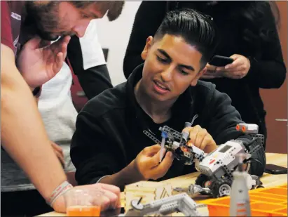  ?? Nikolas Samuels/ The Signal ?? Brian Perez fixes the robot in between heats as Ian Happel looks on during the eco-zomBEE Robot Challenge, hosted by MakerSpace, at College of the Canyons on Thursday.