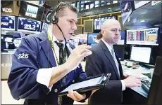 ??  ?? Trader William McInerney (left), and specialist Jay Woods work on the floor ofthe New York Stock Exchange.