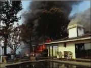  ?? GENARO MOLINA / LOS ANGELES TIMES ?? A firefighte­r walks near a swimming pool as a home is in flames from the Skirball fire along Linda Flora Drive in Bel Air on Wednesday.