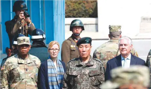  ??  ?? PANMUNJOM: US Secretary of State Rex Tillerson (right) stands with deputy Commander of the Combined Force Command General Leem Ho-young (2nd right) and Margaret Peterlin (2nd left), US Secretary of State Rex Tillerson’s Chief of Staff, as two North Korean soldiers (top) look at the south side at the border village of Panmunjom, which has separated the two Koreas since the Korean War yesterday. — AFP