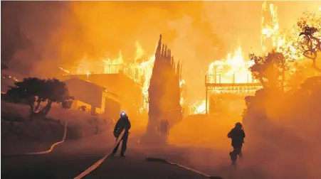  ??  ?? Firefighte­rs work to put out a blaze destroying homes early Tuesday in Ventura, California.