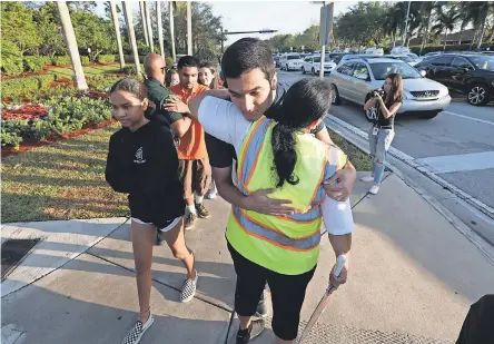  ?? OLIVIA VANNI/NAPLES DAILY NEWS ?? A crossing guard hugs a student near Marjory Stoneman Douglas High School on Wednesday.