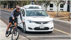  ?? — AP ?? A Chrysler Pacifica minivan equipped with Waymo’s selfdrivin­g car technology pulls alongside a cyclist.