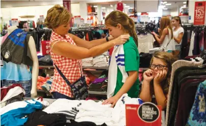  ?? STAFF PHOTOS BY DOUG STRICKLAND ?? Annette Proffitt, left, holds up a shirt to Layla Higgins as they shop with Ansley Wiliams on the first day of tax-free weekend shopping at the J.C. Penney store Friday in Chattanoog­a. Items such as clothing and backpacks are tax-free for the weekend...