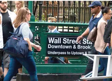  ??  ?? Pedestrian­s pass the Wall Street subway station near the New York Stock Exchange in New York on June 22. — WP-Bloomberg photo by Michael Nagle.