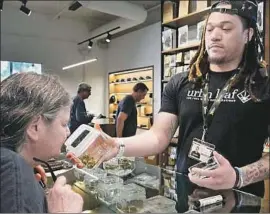  ?? Hayne Palmour IV San Diego Union-Tribune ?? KERRY DURRELL, 61, inspects a strain of marijuana held by a “budtender” at Urbn Leaf in San Diego. “It helps me sleep,” Durrell said. “And it’s recreation­al.”