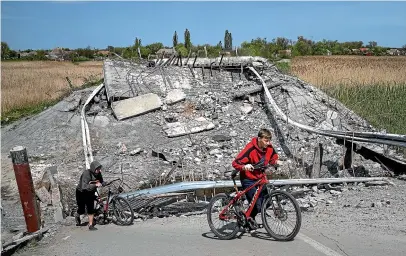  ?? AP ?? Teenagers on bicycles pass a bridge destroyed by Russian shelling near Orihiv, Ukraine. Ten weeks into the devastatin­g war, Ukraine’s military says it has recaptured some areas in the south and repelled other attacks in the east.