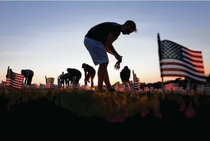  ?? Win McNamee / Getty Images ?? Volunteers with the COVID Memorial Project install 20,000 American flags on the National Mall on Sunday as the United States reaches 200,000 lives lost to the COVID-19 pandemic. The number of dead is equivalent to a 9/11 attack every day for 67 days.