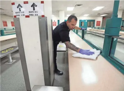  ?? TINA MACINTYRE-YEE/USA TODAY NETWORK ?? Amid the threat from the coronaviru­s, Deputy John Leastman wipes down a counter as part of an extra cleaning in the visitation area of the Monroe County Jail in Rochester.