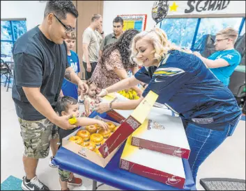  ?? ?? Peter Hyun said he was celebratin­g fathers and sons. Hyun helped son Leo, 2, make his doughnut selection as recreation services supervisor Danielle Perry helped.