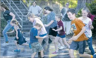  ?? ?? SUPT. GRETA TURNEY sprays water on children at Kneeland, one of the smallest public schools in California. Since 2020, enrollment has more than doubled, to 33 students.