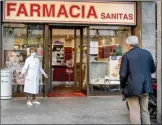  ?? The Associated Press ?? A pharmacist wears a mask as she speaks to a man keeping his distance, outside a pharmacy in Milan, Italy, Wednesday.