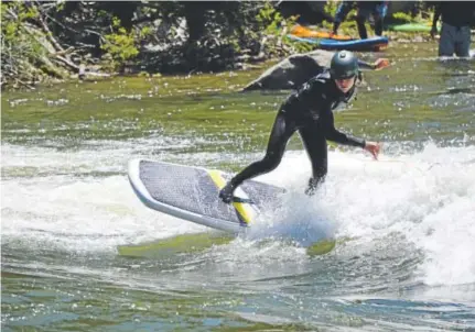  ??  ?? Mike Harvey surfs on a Badfish SK8 board at the Buena Vista riverpark.