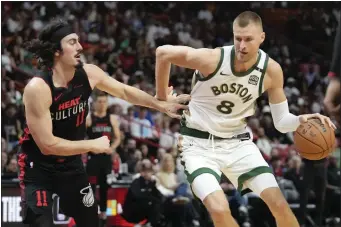 ?? REBECCA BLACKWELL — THE ASSOCIATED PRESS ?? Boston Celtics center Kristaps Porzingis, right, moves the ball while defended by Miami Heat guard Jaime Jaquez Jr. during the first half of an NBA game on Sunday, Feb. 11in Miami.