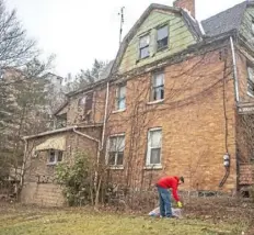  ??  ?? Eli Davis, 13, of Sheraden, picks up trash in front of a condemned house in the neighborho­od.