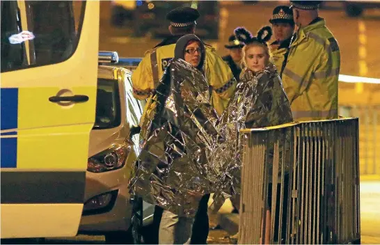  ??  ?? Concertgoe­rs are treated by ambulance staff after an explosion rocked Manchester Arena, where American pop star Ariana Grande was performing, killing at least 22 people.