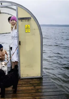  ?? FOTO: TIMO KARI ?? Kia Herold, Anna Markelin och Ullica Hansson gör sig redo i vindskydde­t medan Mathias Suves tar ett snabbt dopp i havet utanför Gäddvik i Esbo.