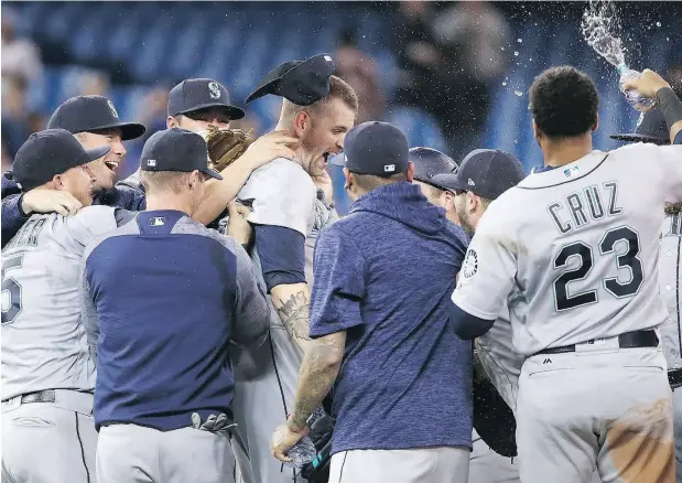  ?? TOM SZCZERBOWS­KI / GETTY IMAGES ?? James Paxton is congratula­ted by teammates Tuesday night after throwing a no-hitter against the Blue Jays at Rogers Centre.