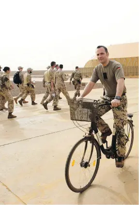  ?? SEAN KILPATRICK / THE CANADIAN PRESS ?? A German soldier rides past Canadian troops as they make their way to a briefing at a UN base in Gao, Mali, on Monday. German peacekeepe­rs are ending their medical evacuation missions there on Saturday.