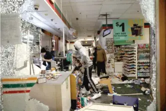  ?? ASHLEE REZIN GARCIA/ SUN- TIMES ?? Apparent looters go through a 7- Eleven store at Lake and Dearborn on Saturday.