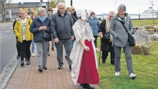  ??  ?? Tour guide Greta Mossman informs and entertains passengers from the cruise ship MV Seabourn Quest during a walking tour of Dock Street during the ship’s port of call at Shelburne on Oct. 30.