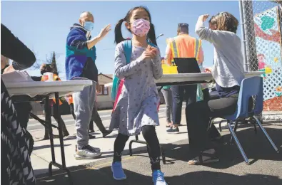  ?? Photos by Jessica Christian / The Chronicle ?? Above: A firstgrade­r arrives for the first day of partial inperson instructio­n at Garfield Elementary School in Oakland. Below: Nikita Williams helps secondgrad­er Ernesto Beltran Pastrana find his classroom.