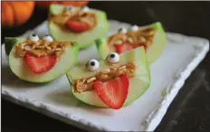  ??  ?? Turn apple wedges into spooky, silly and healthful apple monsters with almond teeth and sliced strawberry eyes.