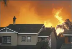  ?? AP file photo ?? Herman Termeer, 54, stands on the roof of his home as the Blue Ridge Fire burns along the hillside in Chino Hills, Calif. An overheatin­g world obliterate­d weather records in 2020 — an extreme year for hurricanes, wildfires, heat waves, floods, droughts and ice melt — the United Nations’ weather agency reported Wednesday.