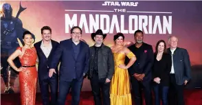  ?? (Mario Anzuoni/Reuters) ?? CREATOR JON FAVREAU (3rd left), Lucasfilm President Kathleen Kennedy (2nd right), executive producer Dave Filoni (center) pose with cast members (left to right) Ming-Na Wen, Pedro Pascal, Gina Carano, Carl Weathers and Werner Herzog at the premiere for the television series ‘The Mandaloria­n’ in Los Angeles in 2019.