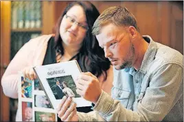  ?? [CHARLIE NEIBERGALL/THE ASSOCIATED PRESS] ?? Lilly Ross shows her family photos to Andy Sandness during their meeting Oct. 27 at the Mayo Clinic in Rochester, Minn. Transplant surgery gave Sandness the face that once belonged to Ross’ husband, Calen “Rudy” Ross.