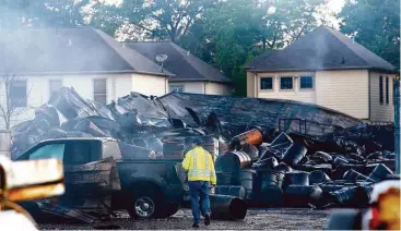  ?? Michael Ciaglo photos / Houston Chronicle ?? Hot spots continue to smoke Friday as a city employee walks through the rubble after a blaze destroyed a warehouse that contained chemicals. Below, SET Environmen­tal employees use absorbent pads in a drainage ditch to soak up chemicals that flowed into...