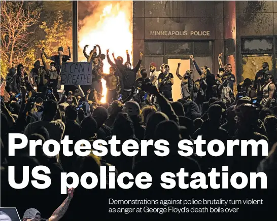  ?? Photo / AP ?? Above: Protesters celebrate after a Minneapoli­s police building was set on fire. Below: A protester holds up a picture of George Floyd.