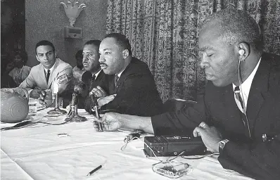  ?? Savannah Morning News via AP
Buddy Rich/Savannah Morning News via AP ?? ■ ABOVE: The Rev. Martin Luther King Jr., center, speaks
with the media Sept. 29, 1964, at the Southern Christian Leadership Conference convention in Savannah, Ga. Ralph D. Abernathy, second from left, and Andrew Young, left, listen. Savannah Morning News photo chief Steve Bisson discovered the image along with 13 other negatives submerged within the newspaper’s old photo files, showing
documentat­ion of two Savannah appearance­s in 1964.
■ RIGHT: In this February 1964 photo, the Rev. Martin Luther King Jr. speaks at the Chatham County Crusade for
Voters in Savannah, Ga.