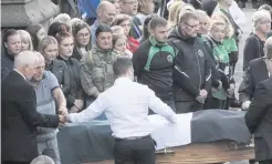  ??  ?? Gerry O’Donnell (second left) removes the Na Magha CLG colours from his son’s coffin after its arrival at St Eugene’s Cathedral