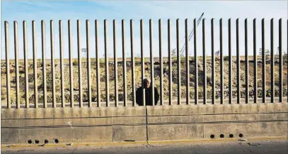  ?? Rodrigo Abd ?? The Associated Press Issac Rodriguez, a homeless man from Sinaloa, Mexico, begs Wednesday near the fence that divides Mexico and the United States in Tijuana, Mexico. As of Wednesday, there were 5,764 active-duty troops performing support missions along the border.