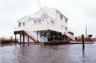  ??  ?? NEW JERSEY: Photo shows Jim and Maryann O’Neill’s home in a back bay neighborho­od of Manahawkin NJ, surrounded by water after a moderate storm. —AP