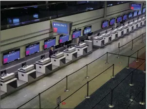  ?? (AP/John Locher) ?? A lone person works April 21 at the Delta Air Lines check-in desk at McCarran Internatio­nal Airport in Las Vegas. The company’s passenger counts fell by 93% in the second quarter.