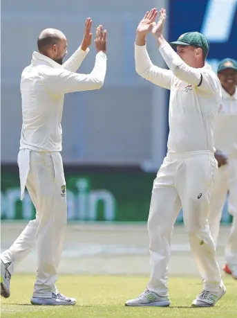  ??  ?? Australia's Nathan Lyon, left, is congratula­ted by Shaun Marsh in the first Test against India