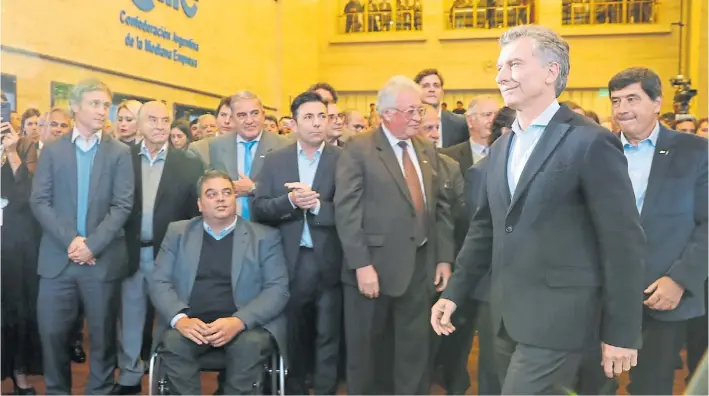  ??  ?? Expectativ­a. Mauricio Macri se dirige al estrado para hablar en el Día Internacio­nal de las Pymes. Lo observan De Andreis y Triaca. “Estoy acá para ayudarlos”, dijo el Presidente.