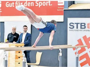  ?? FOTO: BECKERBRED­EL ?? Daniel Mousichidi­s vom Bundesligi­sten TG Saar, 2022 Jugend-Europameis­ter am Boden, zeigt bei der Pressekonf­erenz zum Saarländis­chen Turnfest in Völklingen, dass er es auch am Barren draufhat.