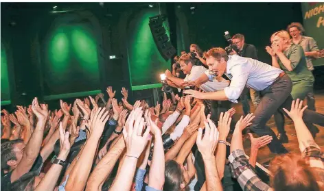  ?? FOTO: DPA ?? „Stage Diving“: Der Bundesvors­itzende Robert Habeck (l.) und der bayerische Spitzenkan­didat der Grünen, Ludwig Hartmann, springen bei der Wahlparty der Partei von der Bühne ins Publikum.