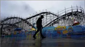  ?? Gregory Bull/Associated Press ?? A worker passes the roller coaster at Belmont Park as rain engulfs the area Tuesday. Stormy weather and the cold, relentless­ly gray skies have clouded California nearly nonstop since late December.